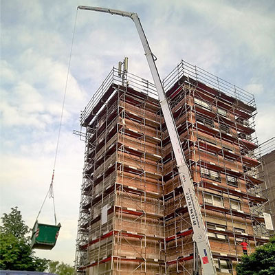 Kran transportiert Schuttmulde an einer Baustelle